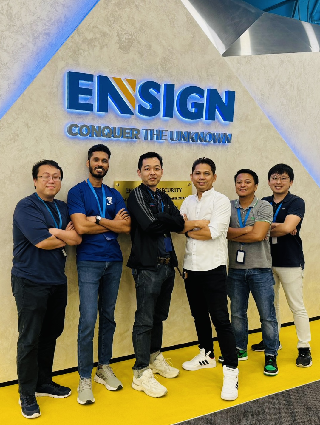 Ensign team photo in front of company logo